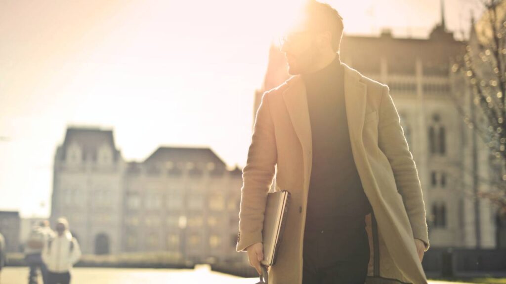 Businessman with a laptop walking down a sunny street